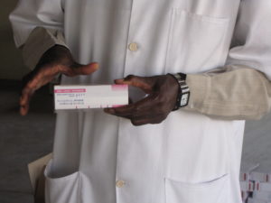 Guinea pharmacist holding malaria medicine. Photo by SIAPS Guinea staff.